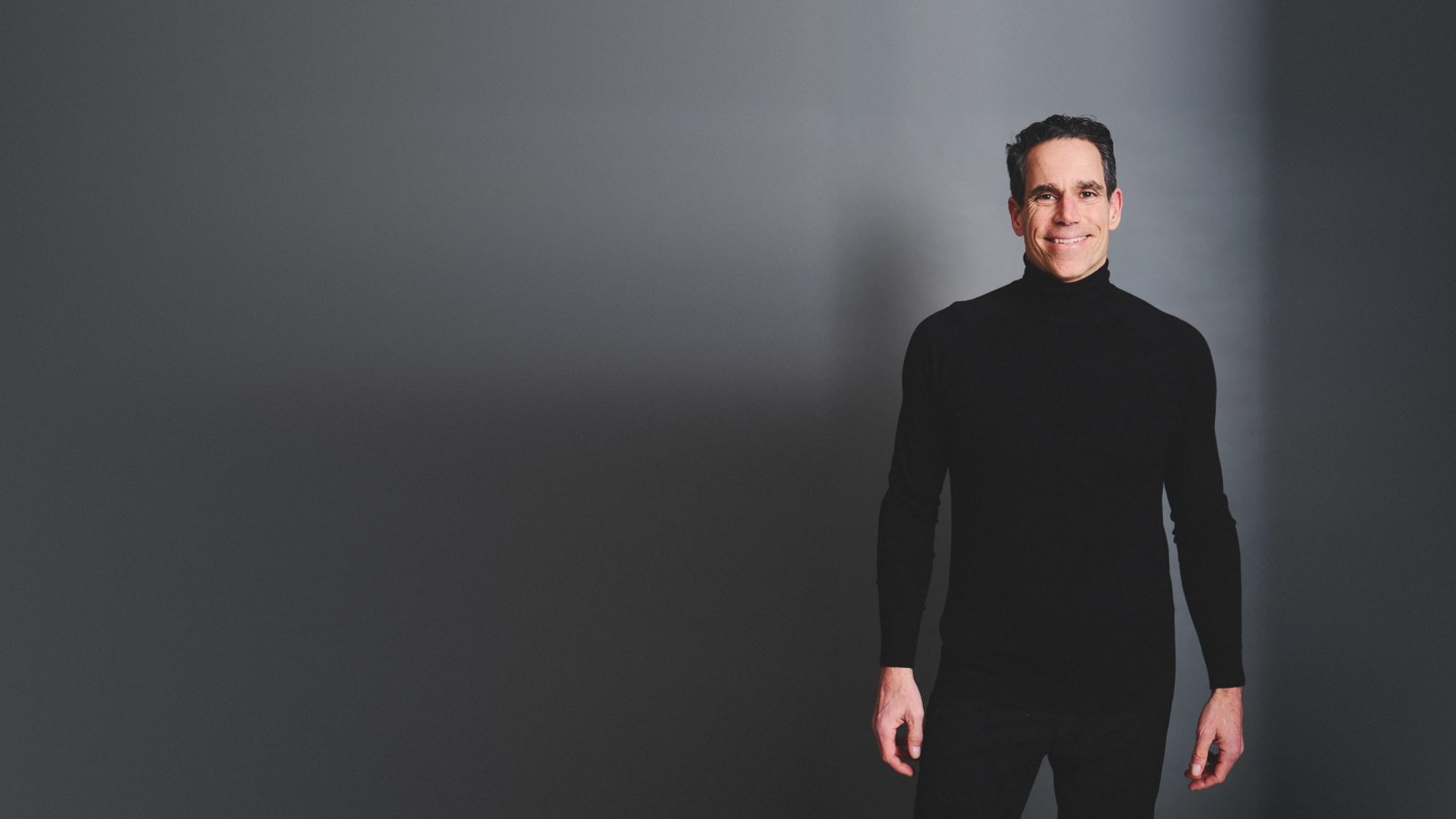 Franco Zuccoli in a black turtleneck, smiling, in the studio